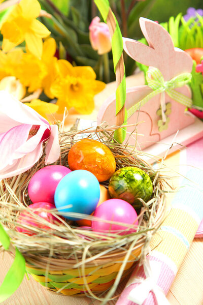Wooden Easter bunny, colorful eggs and bright flowers. Easter concept