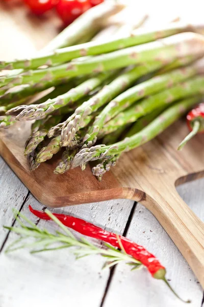 taze kuşkonmaz ahşap kesme tahtası, biber ve biberiye masada görmek