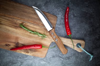 Kırmızı sıcak biber biber, biberiye, bıçak ve gri masada ahşap tahta