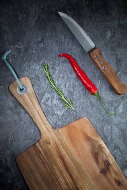 Kırmızı sıcak biber biber, biberiye, bıçak ve gri masada ahşap tahta