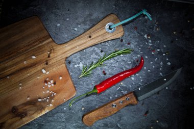 Kırmızı sıcak biber biber, baharatlar, bıçak ve gri masada ahşap tahta