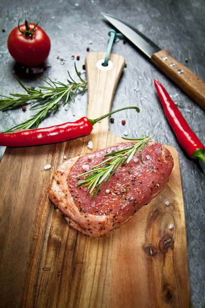 Tahta üzerinde sebzeli ve baharatlı çiğ et.