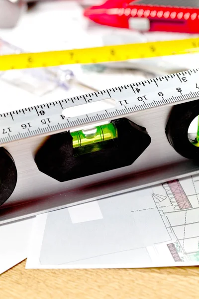 close-up view of level tool, measuring tape and blueprint on table