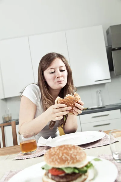 Aantrekkelijke Jonge Vrouw Die Heerlijke Hamburger Thuis Eet — Stockfoto