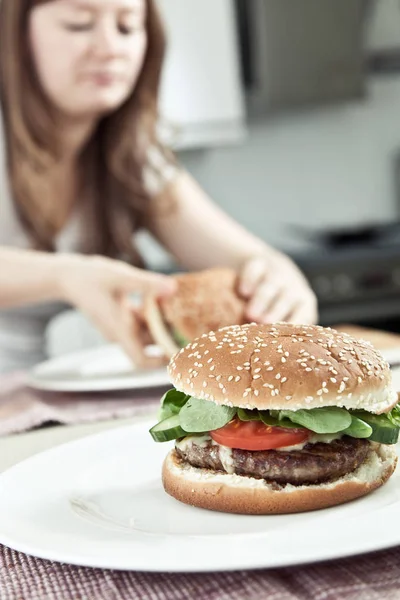 맛있는 햄버거와 부엌에 여자의 클로즈업보기 선택적 — 스톡 사진