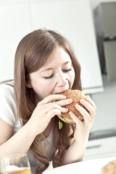 Hungrige Junge Frau Isst Leckeren Hamburger Hause — Stockfoto