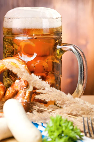 Mug of beer, pretzel and sausages on wooden table. Octoberfest concept