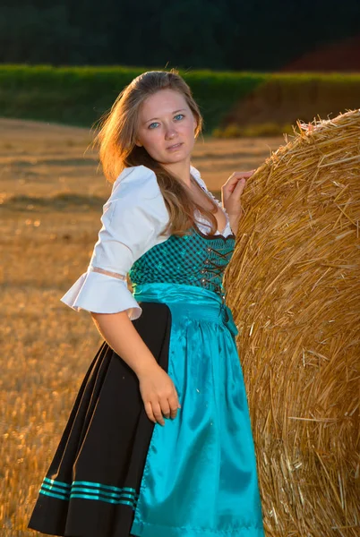 在麦田上摆出干草堆的蓝色礼服的美丽年轻女子 — 图库照片