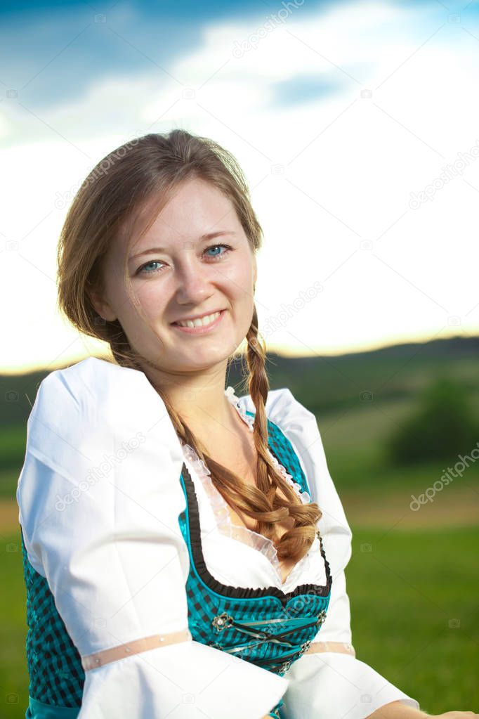 Attractive young woman in blue dress posing on green meadow