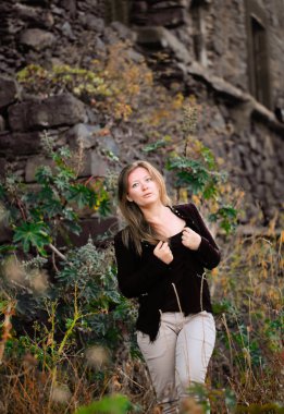 siyah ceketli güzel genç kadın eski taş duvar yakınında açık poz