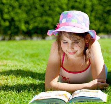 Sevimli çocuk çimenlerin üzerinde yatıyor ve gülümsüyor. 