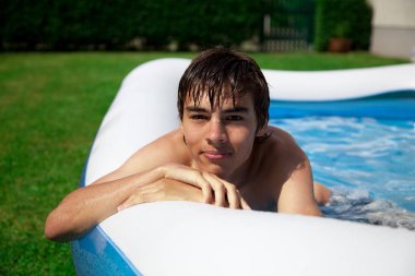 Genç adam havuzda dinleniyor.