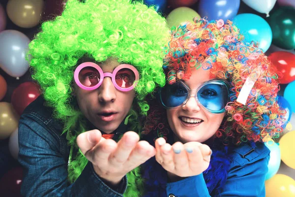 カラフルなウィッグやカラフルなパーティー バルーン背景にポーズのメガネで面白い若いカップル — ストック写真