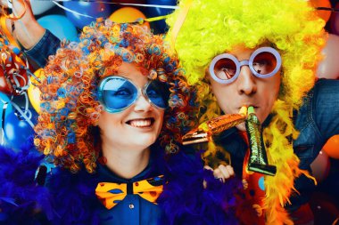 Komik genç çift renkli peruk ve gözlük renkli parti balon arka plan karşı eğleniyor