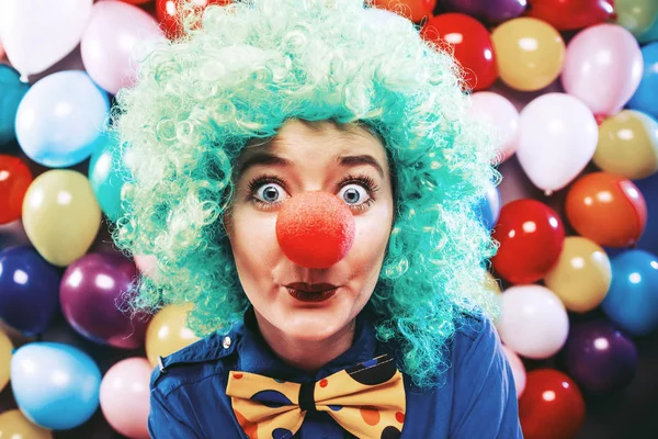 beautiful happy young woman with clown nose looking at camera and celebrating carnival or New Year in party club