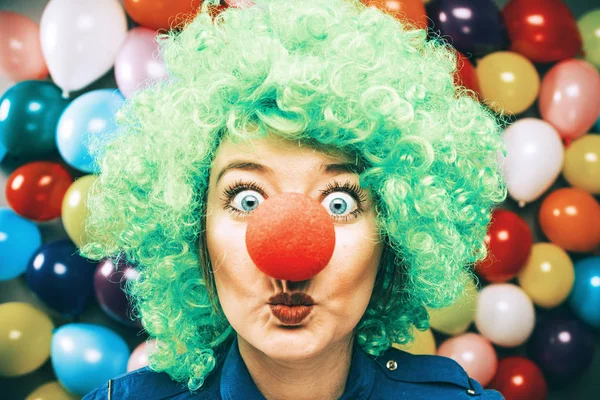 beautiful happy young woman with clown nose looking at camera and celebrating carnival or New Year in party club