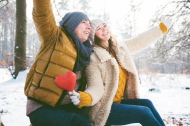 Kırmızı kalp sembol birlikte kış parkta oturan ile mutlu genç Çift 
