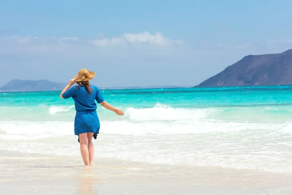 Happy woman traveller in blue dress enjoying her vacation at tropical beach