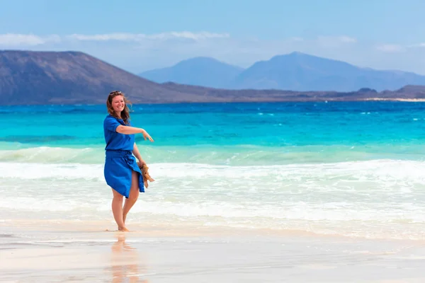 Happy woman traveller in blue dress enjoying her vacation at tropical beach