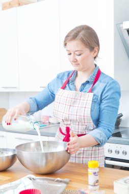 güzel genç kadın süt dökme ve mutfakta hamur hazırlama önlük