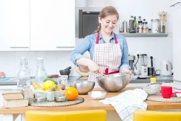 beautiful happy woman in apron preparing dough in kitchen