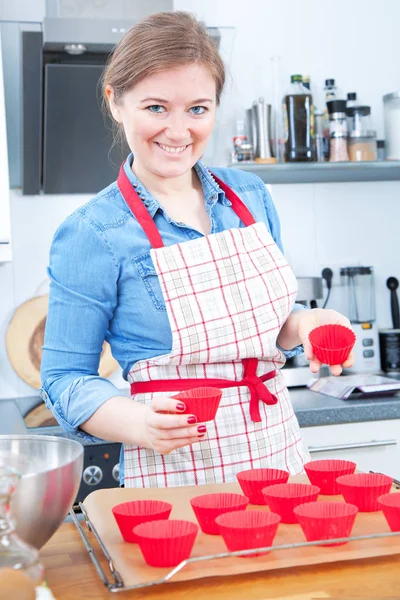 beautiful happy woman cooking cupcakes and smiling at camera in kitchen