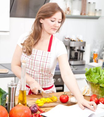 kitabı okuma ve mutfakta sebze salatası hazırlama genç kadın