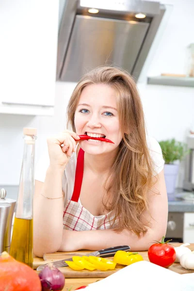 Mooie Jonge Vrouw Schort Bijten Rode Chilipeper Camera Kijken Tijdens — Stockfoto