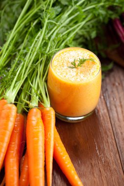 Cam ve ahşap zemin üzerine taze havuç havuç suyu. Sağlıklı gıda kavramı