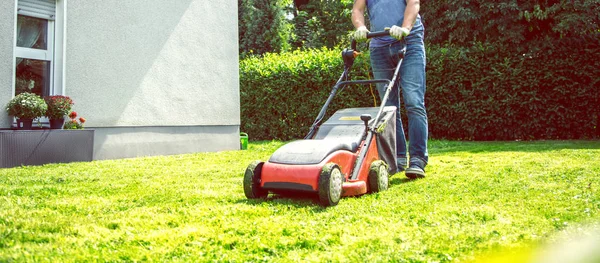 Summer and spring season. Man mowing lawn in the garden during sunny