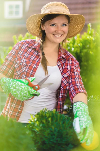 Beautiful smiling young woman gardening outside in summer nature