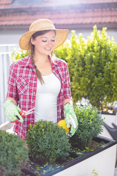 Beautiful smiling young woman gardening outside in summer nature