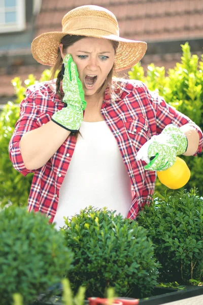 Beautiful surprised young woman gardening outside in summer nature