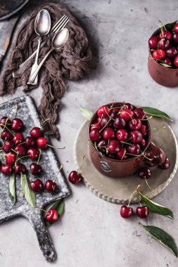 taze kiraz, kaşık, çatal ve gri yüzeyüzerinde tahta ile kupalar üst görünümü