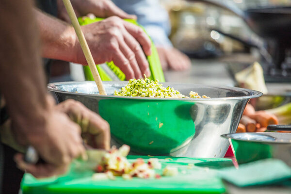 Close up of unrecognizable cook cutting onions and other vegetables with chef knife while working