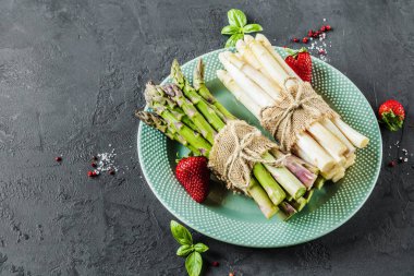 Asparagusand demet çilek plaka kayrak tablo arka plan üzerinde