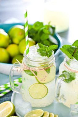 limonata ile mason kavanoz, içme pipetleri, nane, buz küpleri ve dilimlenmiş kireç 