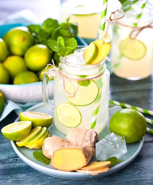 mason jar with fresh cold lemonade, limes and ginger on wooden table
