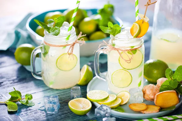 mason jars with fresh homemade lemonade, drinking straws and ice cubes on wooden table