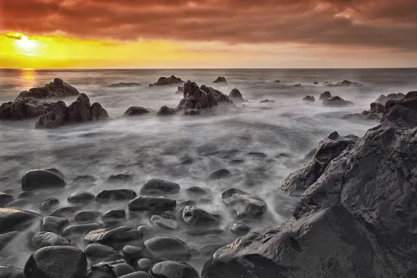 美丽的海景与石头在水和戏剧性多云的天空在日落 — 图库照片