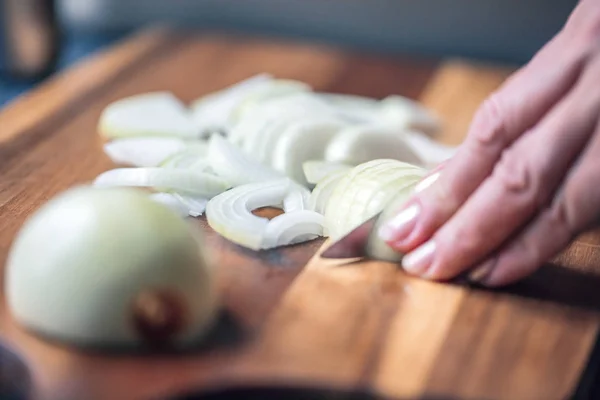 woman cutting white onion with knife Close up
