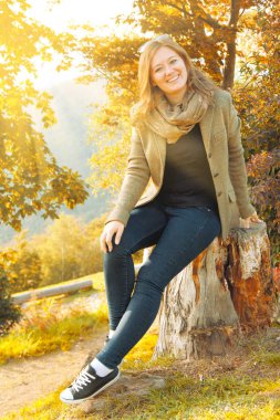 oturma ve kamera sonbahar Park gülümseyen güzel mutlu genç kadın