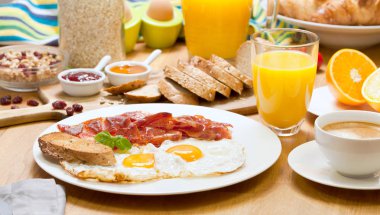 kızarmış ekmek, portakal suyu ve kahve ahşap masa üzerinde lezzetli breakfast için dilimlenmiş pastırmalı yumurta 