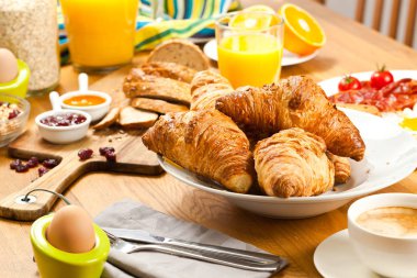 kruvasan, haşlanmış yumurta, kahve, meyve suyu ve müsli ile taze lezzetli kahvaltı ahşap masaya servis