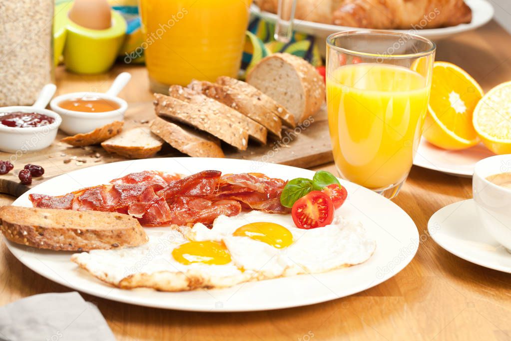 tasty fried eggs with bacon, sliced bread, orange juice and coffee for breakfast on wooden table 