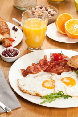 pastırma, cam suyu, yarıya turuncu, reçelli kruvasan ve ahşap masa üzerinde meyveleri ile müsli ile lezzetli kızarmış yumurta