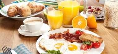 kızarmış yumurta, pastırma, domates, ekmek, portakal suyu, kahve, çilek ve ahşap masa üzerinde kruvasan ile müsli ile lezzetli breakfast