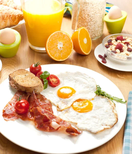 目玉焼きとベーコン チェリー トマト ミューズリー オレンジ ジュース ゆで卵のテーブルの上においしい朝食 — ストック写真