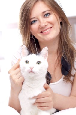 Güzel genç kadın yatakta yatarken ve kameraya gülümseyen şirin kedi ile