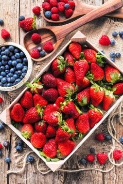 ahşap masa üzerinde taze organik çilek, ahududu ve yaban mersini üstten görünüm